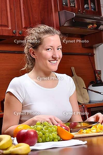 Happy woman is cooking fruit salad [IBR124906345]