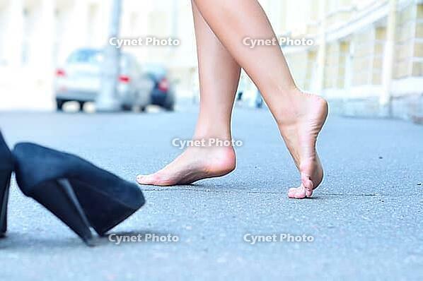 Female bare feet dancing on summer street [IBR124906352]