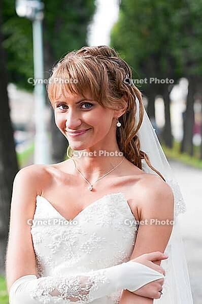Smiling young bride is standing in city park [IBR124906368]