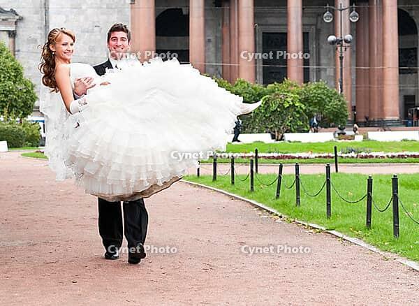 Groom is carrying bride on arms on city park road [IBR124906370]