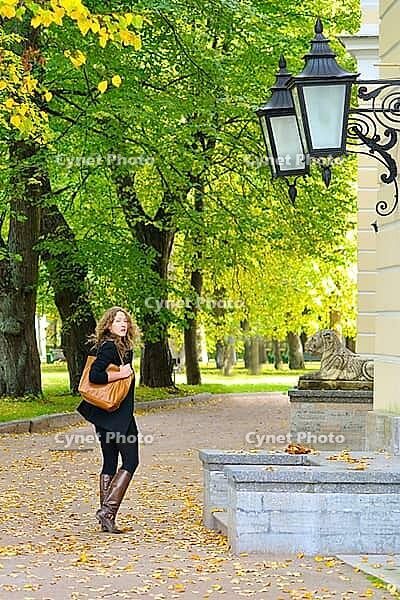 Woman is walking at autumn city park [IBR124906382]