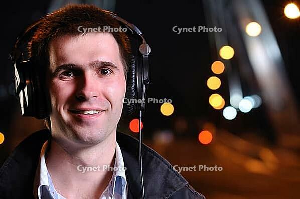 Smiling man is listening music at city night street [IBR124906390]