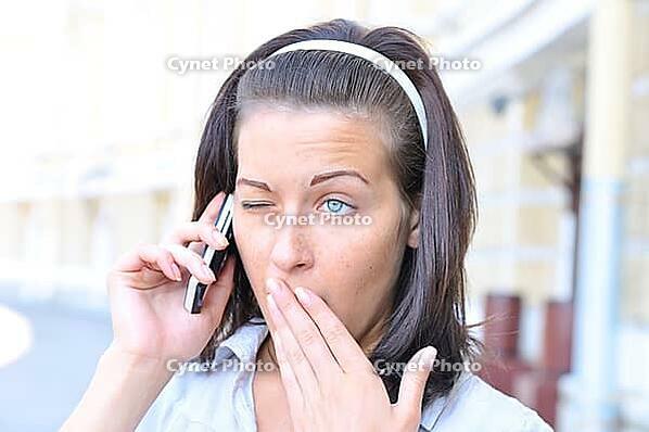 Funny woman is yawning when talking phone [IBR124906393]