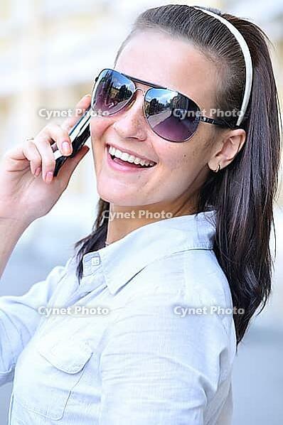 Happy woman is looking back and talking phone [IBR124906413]