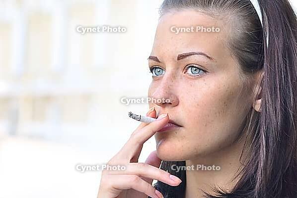 Closeup of a pretty woman smoking at the street [IBR124906419]