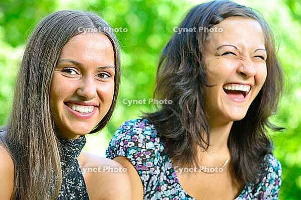 Two female friends is laughing in sunny park [IBR124906421]