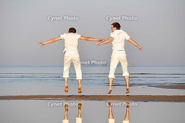 Two friends is jumping at morning beach [IBR124906424]