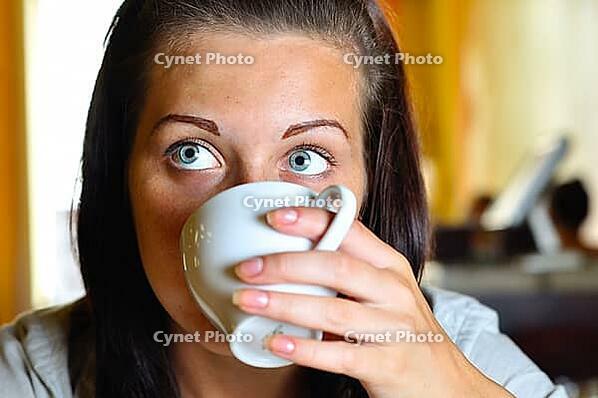 Young woman is drinking coffee in cafe and looking sideways [IBR124906426]