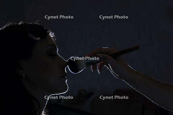 Woman is applying makeup in dark [IBR124906427]