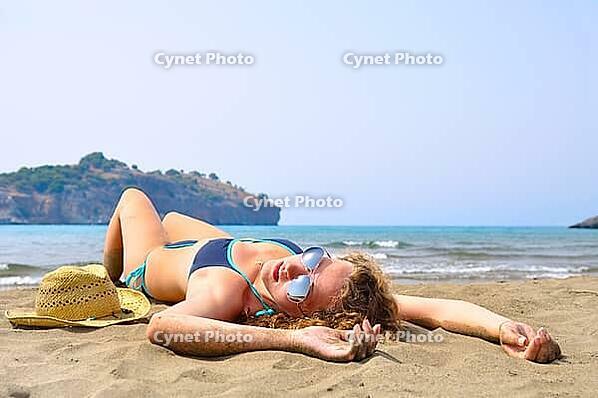 Sexy woman is lying on the beach and looking at camera [IBR124906431]