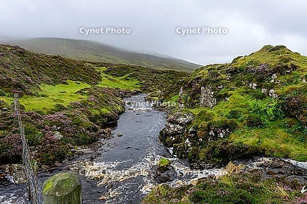 View of the Scottish Highlands, green meadows, cloudy skies and a river in summer 2018 [IBR124915230]