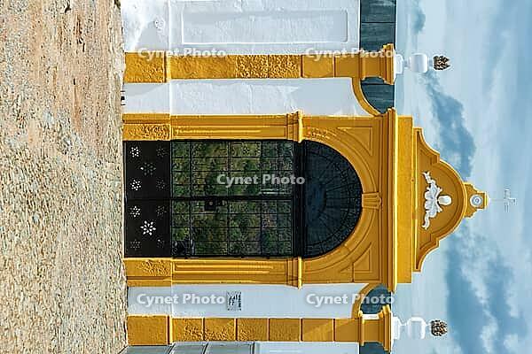 View of a black gate with a yellow border in a white wall in Mertola in spring 2019 [IBR124915275]