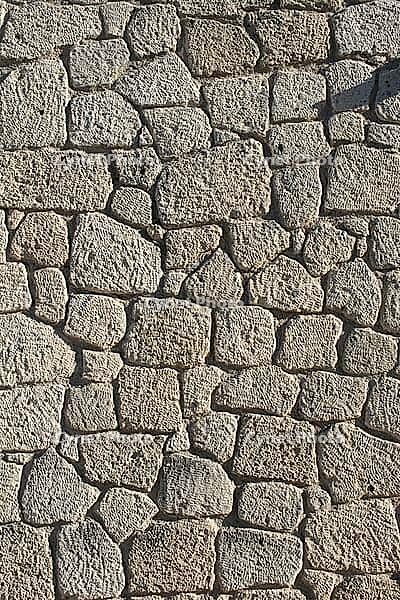 Close view of aged stone wall showing rough texture, natural pattern, and rustic architectural detail [IBR124920162]