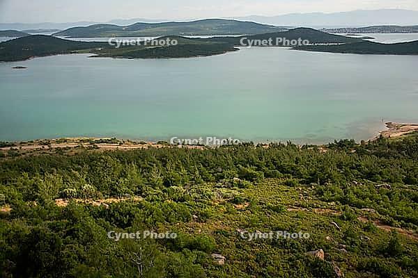 A tranquil panorama of Ayvalık's emerald islands and calm waters unfolds beneath soft, drifting clouds [IBR124920168]