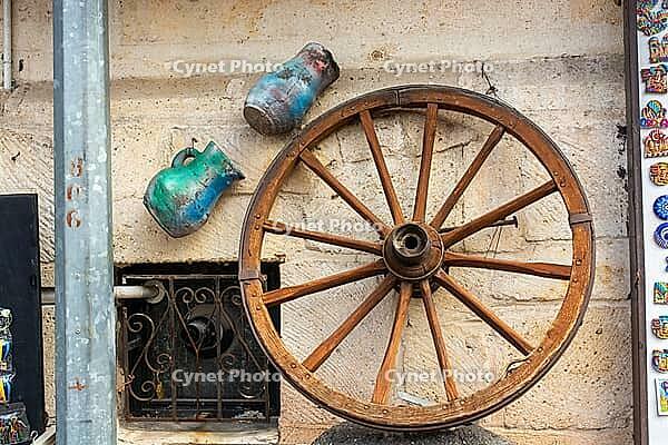 A rustic bicycle wheel hangs on a whitewashed wall, embodying coastal charm and timeless simplicity [IBR124920176]