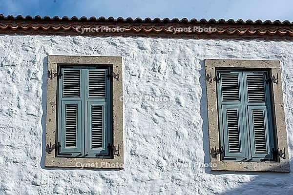A vibrant rustic windows Mediterranean charm through vivid shutters and textured stone facades [IBR124920194]