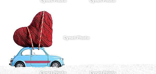 Blue retro toy car delivering heart for Valentine's day on white background [IBR124944049]