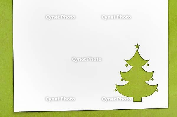 Cut paper in fir-tree shape for christmas card or new year background on green table [IBR124944059]