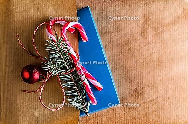 Christmas or new year decoration for gift box of two candy cones with fir-tree branch and toy glass ball on craft paper background [IBR124944072]