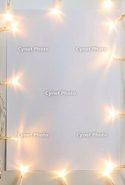 Christmas lights on gray table with paper sheet, view from above [IBR124944073]