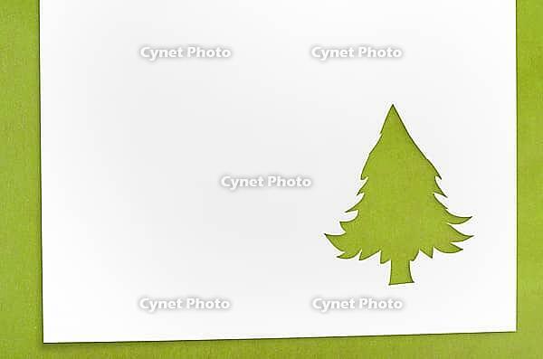 Cut paper in christmas tree shape for christmas card or new year background on green table [IBR124944075]