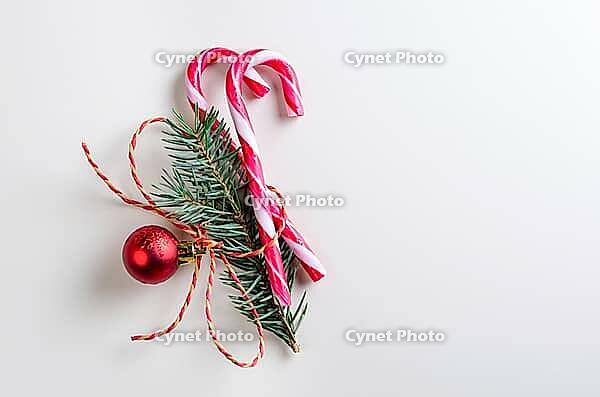 Christmas or new year decoration of two candy cones with fir-tree branch and toy glass ball on gray background [IBR124944080]