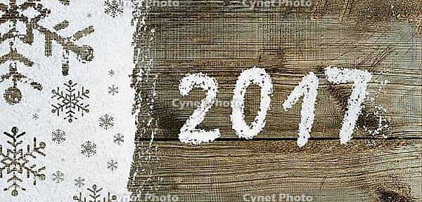 Christmas card or new year background made of snowflakes symbols handwritten on snow and wooden table [IBR124944087]
