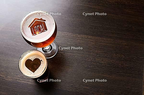 Loving local craft beer. House and heart silhouettes in two glasses of fresh beer on pub table, view from above [IBR124944132]