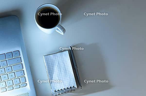 Modern laptop on evening work place, coffee cup and notebook with pen, view from above [IBR124944133]