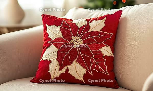 Muted red pillow with ivory poinsettia print and gold stitching details, placed on a pale cream sofa. AI generated [IBR125000269]