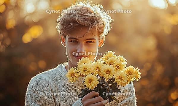 Closeup portrait of a man with sandy blonde hair, holding yellow chrysanthemums. AI generated [IBR125000311]