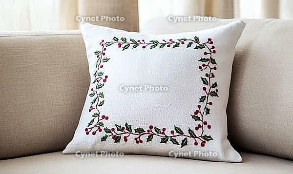 White linen pillow with red and green holly embroidery, set against a beige sofa in a minimalist living room. AI generated [IBR125000316]