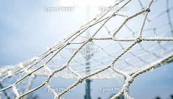 White nylon goal net filling entire frame edge to edge caught mid-violent-vibration with diamond mesh pattern distorted and stretched in multiple directions simultaneously, sharp at centre and motion-blurred at edges showing physical resonance from powerf [IBR125000330]