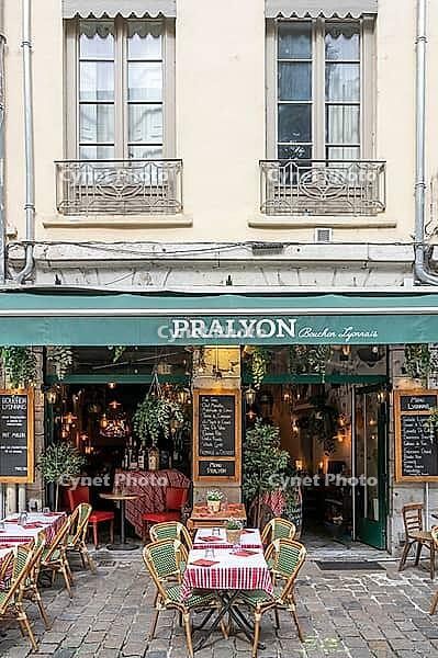 Terrace of the traditional Bouchon Pralyon on the sidewalk of Rue Saint-Jean in the Vieux Lyon district with red and white checkered tablecloths, typical bistro chairs and a handwritten menu with Lyonese specialities, Lyon, Rhone, Auvergne-Rhone-Alpes, Fr [IBR125002340]