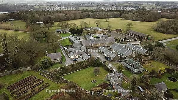 Aerial view of a large rural estate with various buildings and gardens surrounded by fields and trees, Farm in Wales, United Kingdom [IBR125026138]