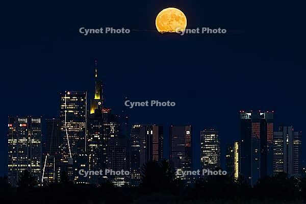 The full moon sweeps across Frankfurt's banking skyline. In June, the full moon is traditionally called the strawberry moon and refers to the strawberry harvest. Rose moon because of the rose blossom and honey moon because of the honey harvest are also tr [IBR125026185]