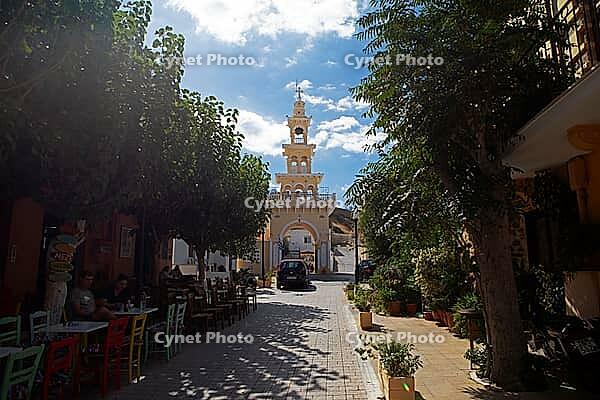 Greek Orthodox Evangelistria church in an alley with colorful chairs, flowers and trees, Paleochora, Kandanos-Selino municipality, Chania Regional Unit, Crete, Greece [IBR125026186]