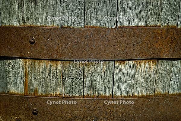 A close-up of an old wooden barrel held together with rusty metal hoops. weathered wood backdrop for garden, rustic charm, or other creative backgrounds [IBR125026210]