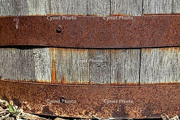 A close-up of an old wooden barrel held together with rusty metal hoops. weathered wood backdrop for garden, rustic charm, or other creative backgrounds [IBR125026212]