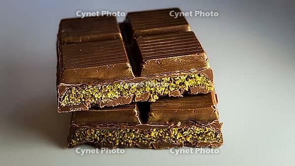 Dubai chocolate with pistachio cream filled center. sliced and stacked for presentation. macrophotography close-up background [IBR125026213]