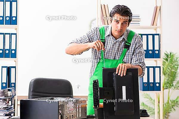 Young engineer repairing broken computer at the office [IBR125053197]