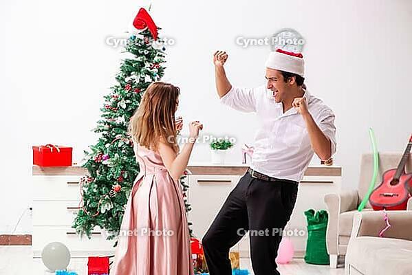 Young pair celebrating christmas at home [IBR125053202]