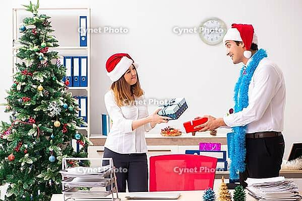 Colleagues exchaing christmas presents in office [IBR125053225]