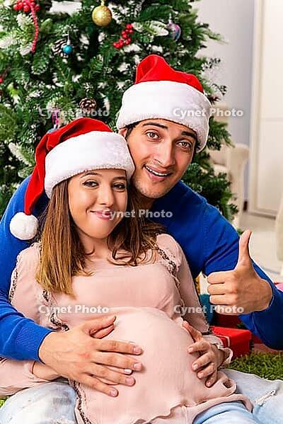 Pregnant wife celevrating christmas with husband [IBR125053266]