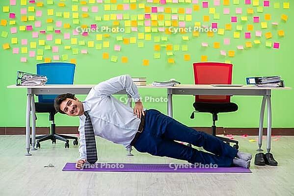 Man in the office with many conflicting priorities doing exercises [IBR125062161]
