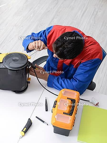 Man repairman repairing vacuum cleaner at service center [IBR125062164]