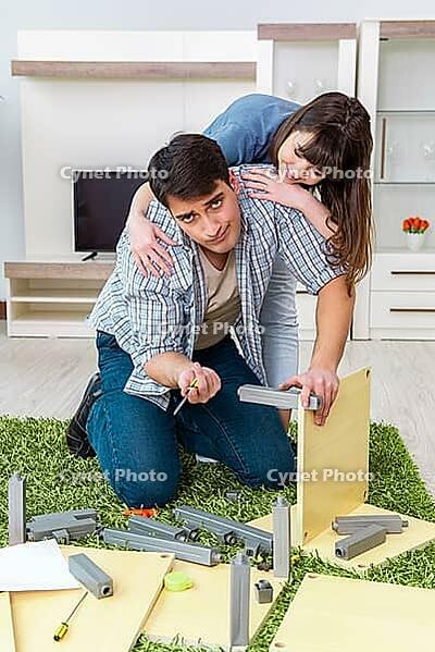 Young family assembling furniture at new house [IBR125062170]
