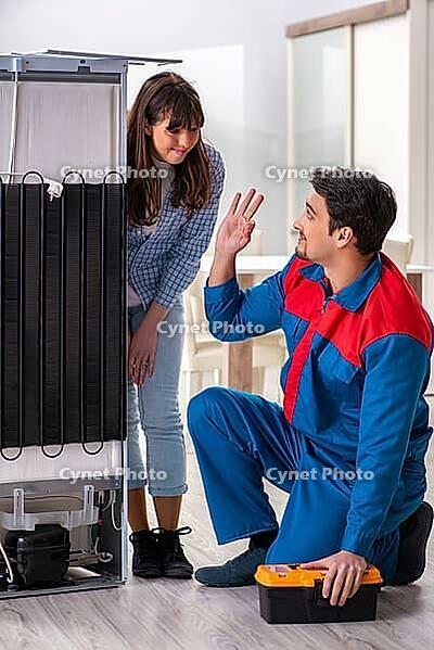 Man repairing fridge with customer [IBR125062171]