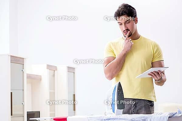 Handsome man husband doing clothing ironing at home [IBR125062185]