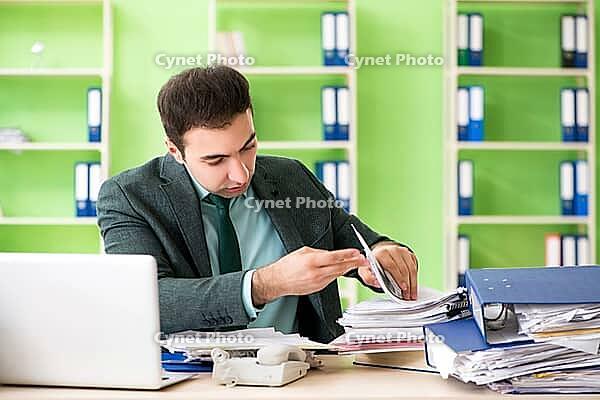 Businessman angry with excessive work sitting in the office [IBR125062191]